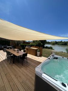 a wooden deck with a table and a hot tub at SPA et SAUNA de la presle in Saint-Georges-sur-Arnon