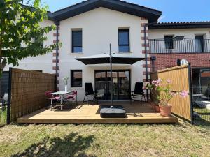 a deck in front of a house with an umbrella at Petite maison cosy avec jardin in Gujan-Mestras