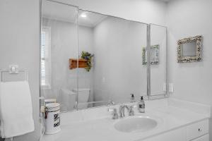 a white bathroom with a sink and a large mirror at 219 Olive Way in East End +20 photos