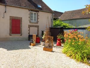 a yard with a house with a red door and some plants at Maison en Pays d'Othe in Les Sièges
