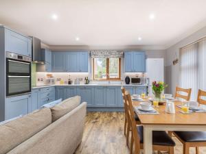 a kitchen with blue cabinets and a table and a couch at 2 bed in Dereham 86115 in Bawdeswell