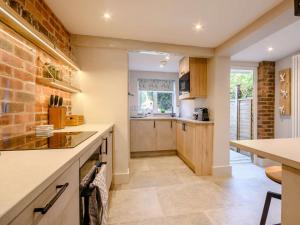 a kitchen with wooden cabinets and a brick wall at 2 Bed in Evesham 88722 in Bretforton +10 photos
