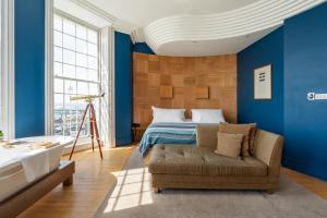 a bedroom with blue walls and a bed and a couch at Drakes Hotel in Brighton & Hove