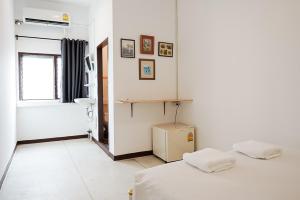 a white room with two beds and a window at GO INN Asiatique BKK - โกอินน์ เอเชียทีค เจริญกรุง in Godown