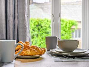 Una mesa con platos de croissants y tazas sobre ella. en 2 Bed in Cockermouth 87481, en Cockermouth 7 fotos más