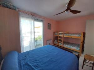 Un dormitorio con una cama azul y un ventilador de techo. en DUPLEX T3 Terrasse proche mer, en Narbonne-Plage