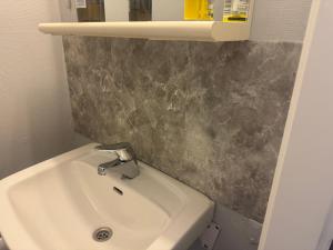 a bathroom with a white sink and a gray wall at Small apartment in Elnesvågen in Svinøya +1 photo