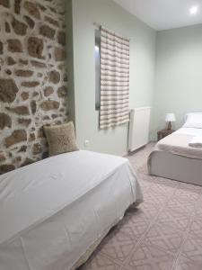 a bedroom with a bed and a stone wall at Katerina's Home in Ancient Epidavros