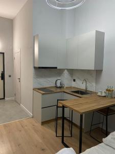 a kitchen with white cabinets and a wooden table at Etalon Apartment in Zhezdi