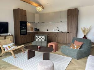 a living room with chairs and a table and a kitchen at 766 - Maison moderne avec piscine privative. in Erquy