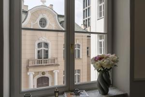 a window with a vase of flowers and a building at La Belle Epoque - LoftAffair Collection in Warsaw