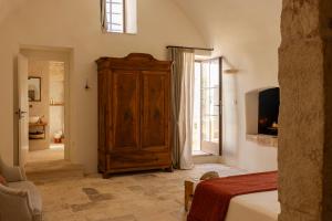 a bedroom with a large wooden cabinet and a television at Masseria Tarsia Morisco in Polignano a Mare