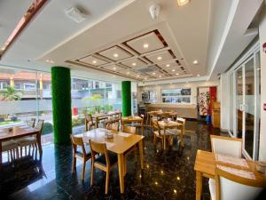 a restaurant with wooden tables and chairs and green pillars at Famous Maple Hotel in Angeles
