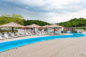 a pool at a resort with chairs and umbrellas at Casute Enea Baile Figa cu Aer condiționat in Agrişu de Sus