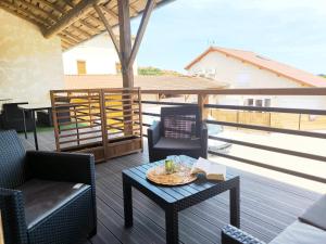 a patio with chairs and a table on a deck at Duplex avec terrasse proche Pérouges Meximieux CNPE BUGEY in Faramans