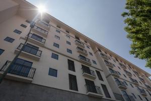 a tall white building with windows and the sun at Beautiful cozy apartment in Cusco