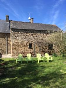 eine Gruppe grüner Stühle vor einem Backsteingebäude in der Unterkunft Gîte Aronde in Roz-sur-Couesnon