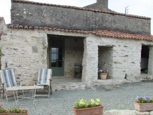une maison en pierre avec deux chaises et une fenêtre dans l'établissement Les Puvinieres, à Breuil-Barret