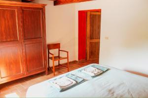a bedroom with a bed with a wooden cabinet and a chair at Podere tra gli Ulivi - Yoga, Natura e Silenzio in Parrano