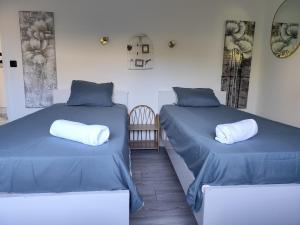 two beds in a room with blue sheets and white pillows at Proche Paris, Aéroports Roissy Charles de Gaulle, Bourget, Parc des Expositions Villepinte in Arnouville-lès-Gonesse