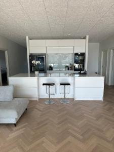 Una cocina con gabinetes blancos y dos taburetes de bar. en Beautiful gem in a quiet setting, en Svendborg 11 fotos más