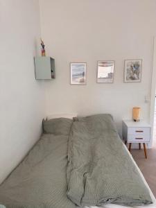 Una cama en un dormitorio blanco con una mesita de noche. en Beautiful gem in a quiet setting, en Svendborg