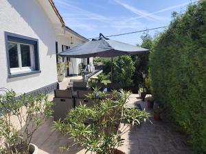 a patio with an umbrella and chairs and plants at Proche Paris, Aéroports Roissy Charles de Gaulle, Bourget, Parc des Expositions Villepinte in Arnouville-lès-Gonesse