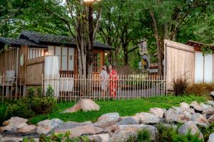 two women standing near a fence in front of a house at Tanuki house Khaoyai in Ban Bung Toei