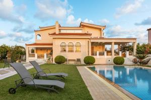 a house with a swimming pool and two chairs in the yard at Renko Royal Villa - Private Infinity Pool & Garden - Athens Riviera in Lagonissi