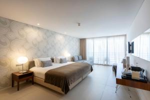 a bedroom with a large bed and a television in it at Troia Design Hotel in Troia