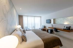 a hotel room with a large bed and a desk at Troia Design Hotel in Troia
