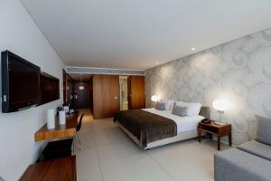 a bedroom with a bed and a tv and a couch at Troia Design Hotel in Troia