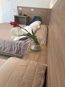 a vase of flowers on a table in a bedroom at Hotel Berna in Eraclea Mare