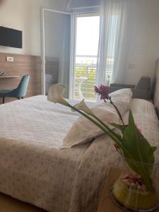 a bedroom with a bed with a vase of flowers on it at Hotel Berna in Eraclea Mare