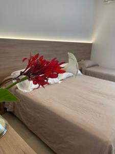 a red and white flower sitting on top of a bed at Hotel Berna in Eraclea Mare