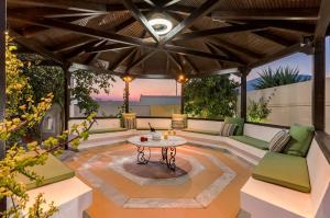 an outdoor patio with a table and green furniture at Renko Royal Villa - Private Infinity Pool & Garden - Athens Riviera in Lagonissi
