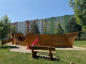 a playground in a park with a slide and a bench at Apartment Spišská Nová Ves in Spišská Nová Ves