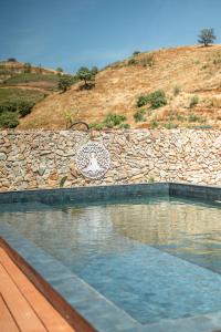 a swimming pool in front of a stone wall at Portugals Infinity - Fantástica casa de campo com vista de mar em Tavira in Tavira
