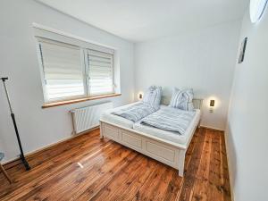 a bedroom with a bed and a window and wooden floors at De lütt Dörpkieker am Torgelower See in Torgelow am See