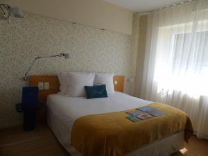 a bedroom with a large bed with a yellow blanket at Hôtel De La Vallée in Dinard