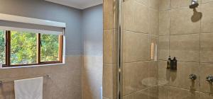 a bathroom with a shower with a glass door at Boabab at Greenway Woods in White River +5 photos