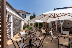 an outdoor patio with tables and chairs and umbrellas at Kálvária panzió in Tata +41 photos