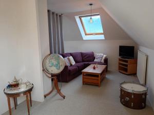 a living room with a purple couch and a table at la maison de la Felicidad in Boussy
