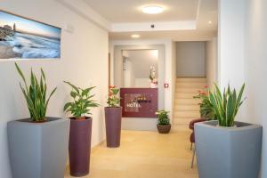 a lobby with three large pots with plants in it at Hotel Capinera in Caorle