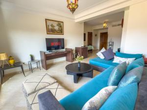 马拉喀什Elegant 2-BR, Pool And Parking Hivernage Centre的客厅里有一张蓝色沙发和一台电视