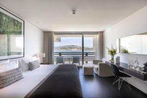 a bedroom with a large white bed and a desk at Troia Design Hotel in Troia