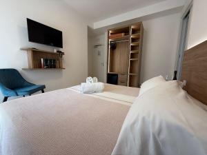 a bedroom with a large white bed and a chair at Hotel Berna in Eraclea Mare