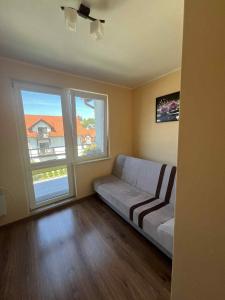 a living room with a couch and two windows at Apartament Niska 10 Krynica Morska in Krynica Morska
