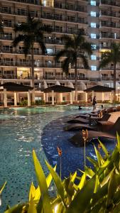 a swimming pool with a large building in the background at Shell Residences MOA - Josh staycation in Manila