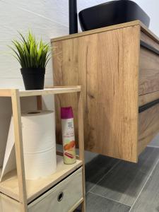ein Holzschrank mit Toilettenpapier und einer Pflanze in der Unterkunft Habitación privada en piso compartido cerca del Centro Alicante in Alicante